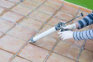 applying silicone on the boards of a tiled floor