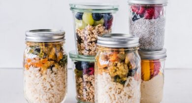 Glasburkar med lock fyllda med ris, grönsaker, granola och frukt